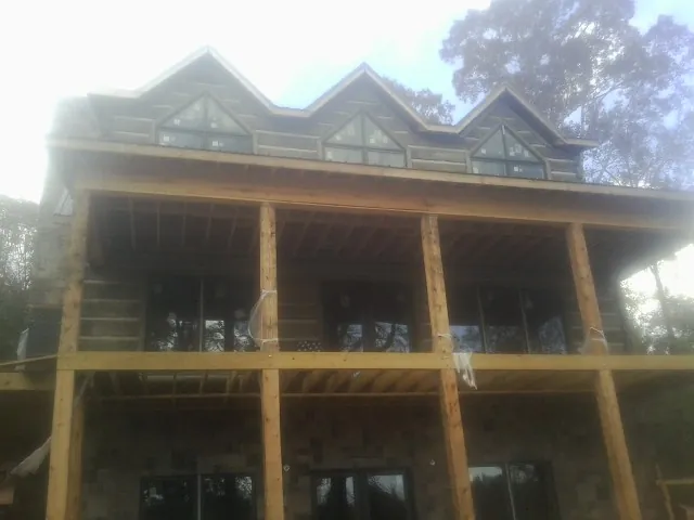 Dormers and porch framing on a large log home under construction — Roof Coating work by our crew in Fraser